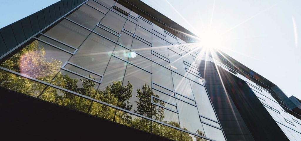 Sunlight glares off the roof of a tall, commercial building.