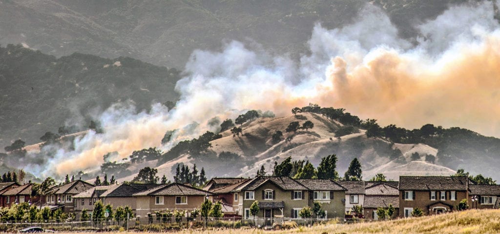 Wildfires encroach onto the backside of a California housing community.