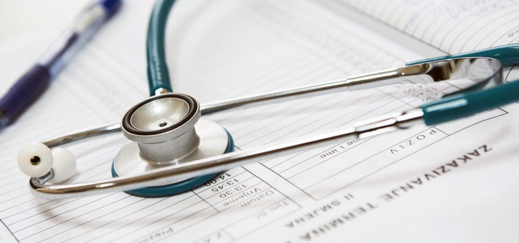 A doctor's stethoscope sits on top of a patient's medical chart.