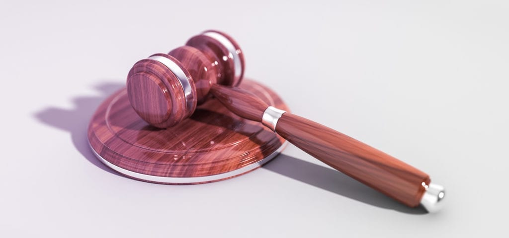 A judge's polished gavel resting on a white surface.