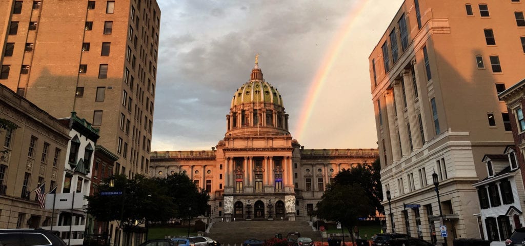 The Pennsylvavnia state capitol building in Harrisburg, Pennsylvania with a rainbow behind it.