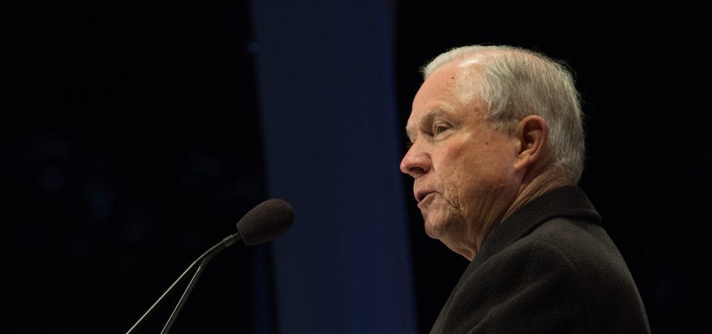 Side portrait photo of Attorney General Jeff Sessions speaking at a candlelight vigil.