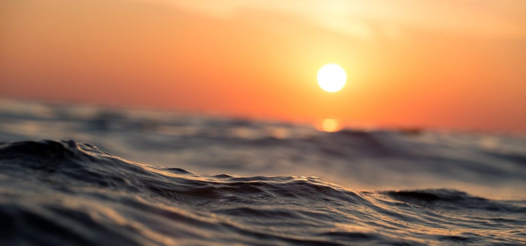 Camera at water-level looking at the sunset on the ocean.