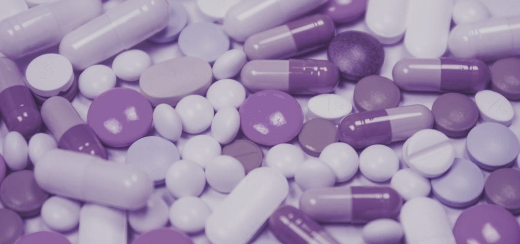 A pile of pharmaceutical medications sprawled onto a flat, white surface.