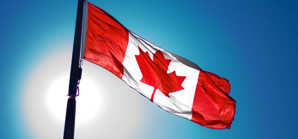 The national flag of Canada flies on a blue-skied, sunny day.