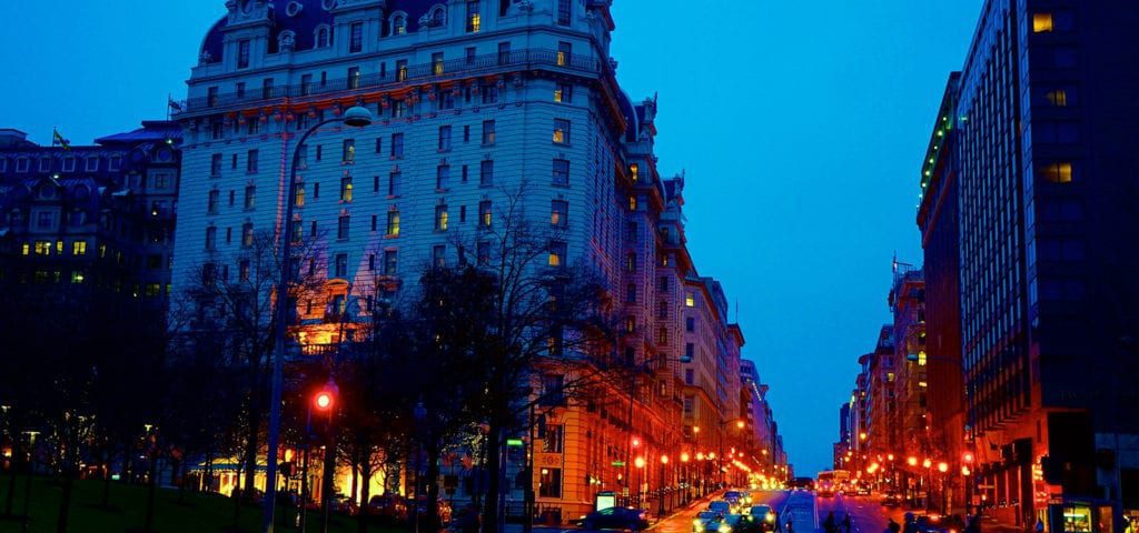 A Washington D.C. street bathed in blue and orange light at sundown.