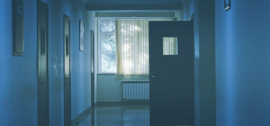 An open door at the end of a hospital hallway.