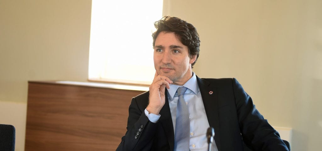 Canada's Prime Minister Justin Trudea sits at a desk with hand on chin.