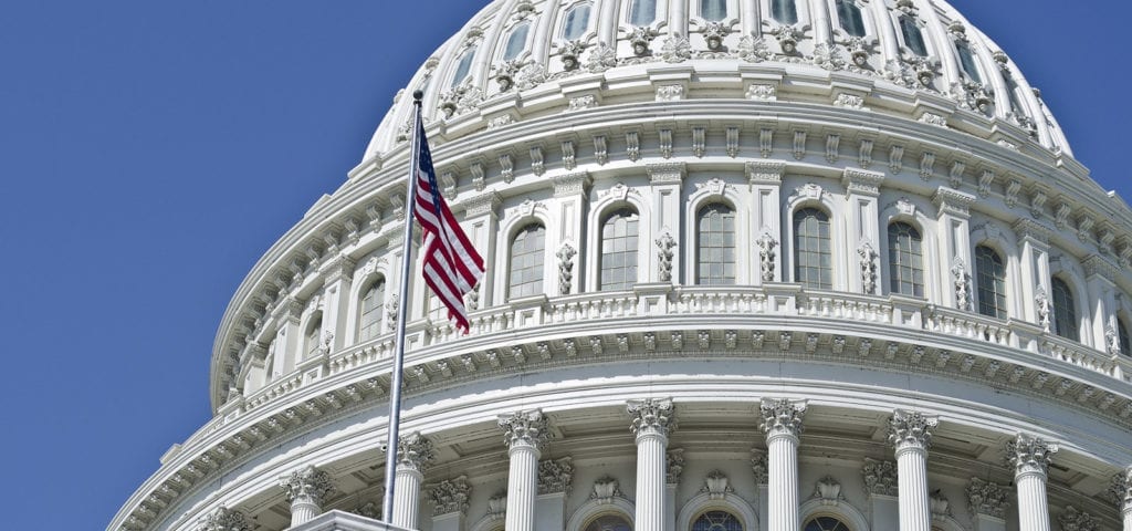 The U.S. flag flying in front of domed top of the Capitol Building in Washington D.C.