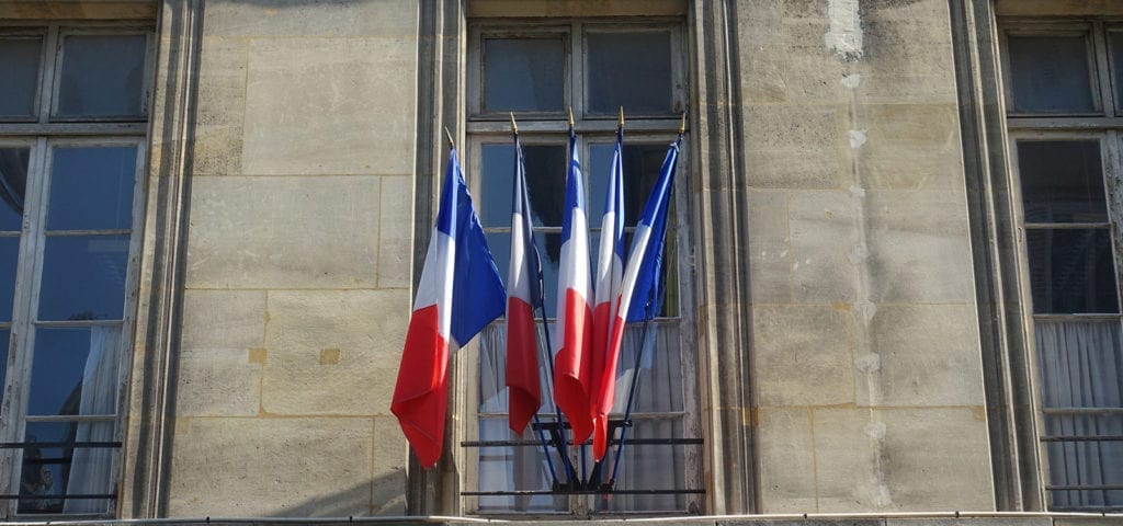 A row of French flags sticking out of a balcony in Paris. France.