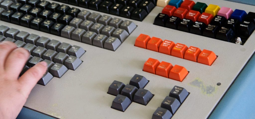 A person with their hands on the keys of a complex keyboard console.