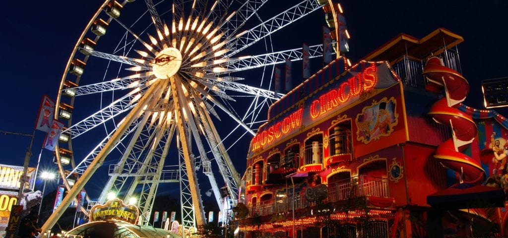 Nighttime photograph of the neon lights on a Ferris Wheel and the "Moscow Circus" attraction inside the Costa Mesa Fairgrounds.