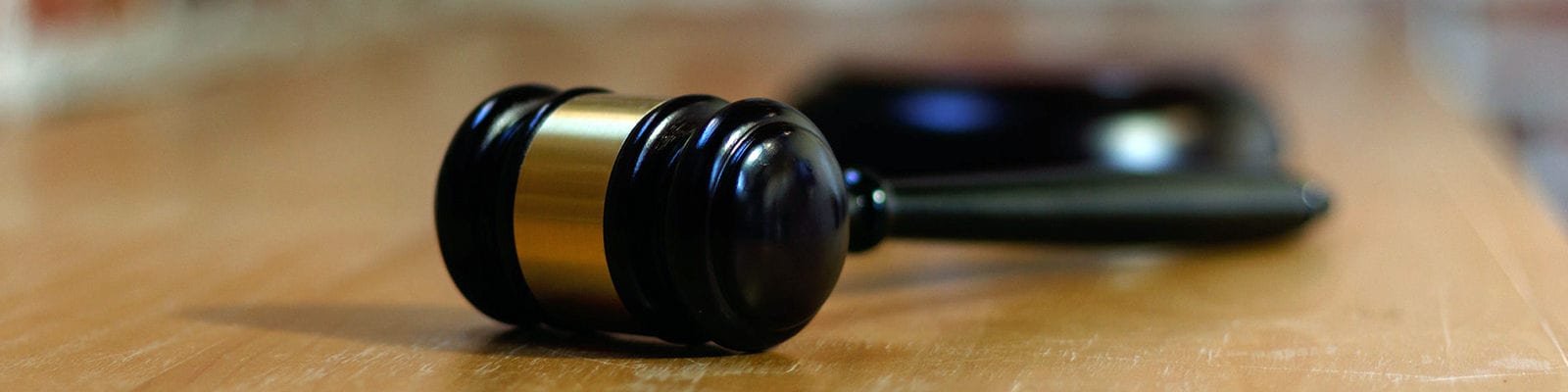 Photo of a judge's gavel lying on its side on a wooden surface.