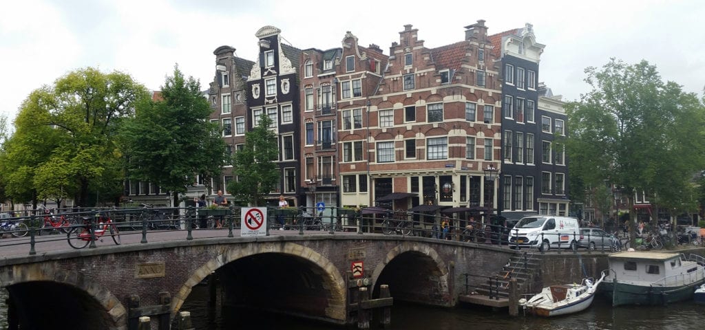 A bridge with people on it and houses behind it in Amsterdam.