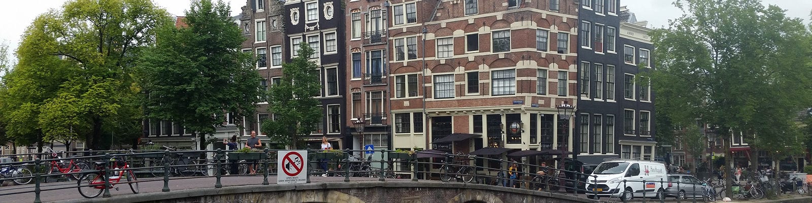 A bridge with people on it and houses behind it in Amsterdam.