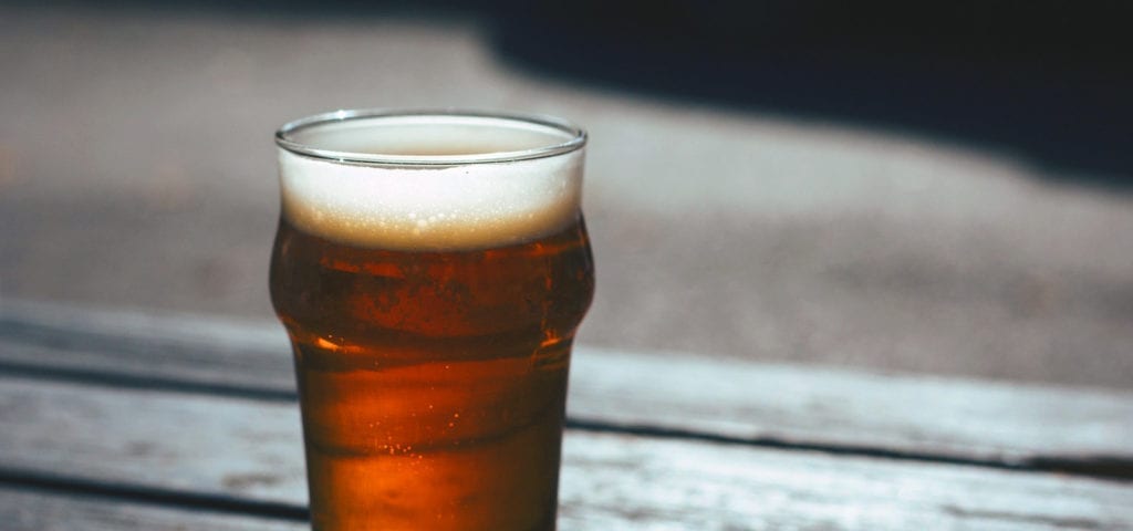 A full pint of beer sits on a wooden surface.