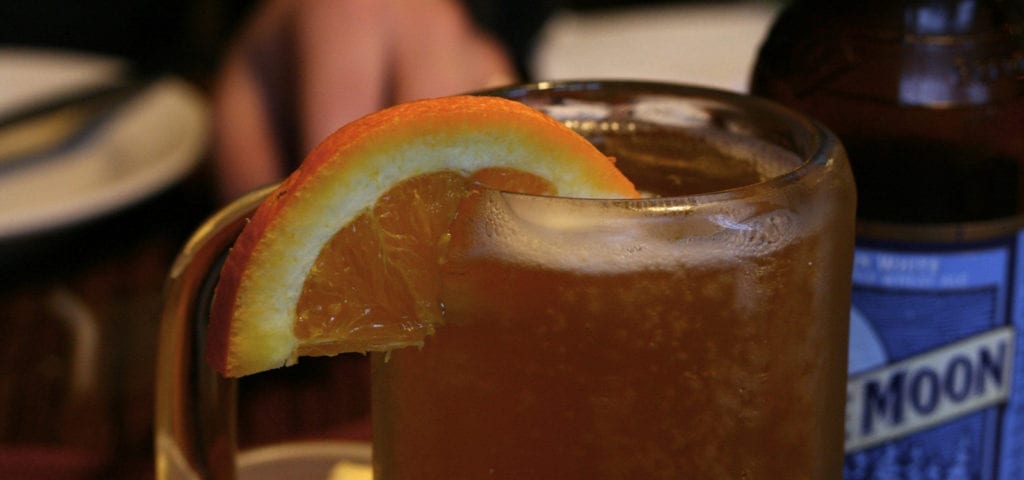 A blue moon beer poured into a chilled mug and served with an orange slice.
