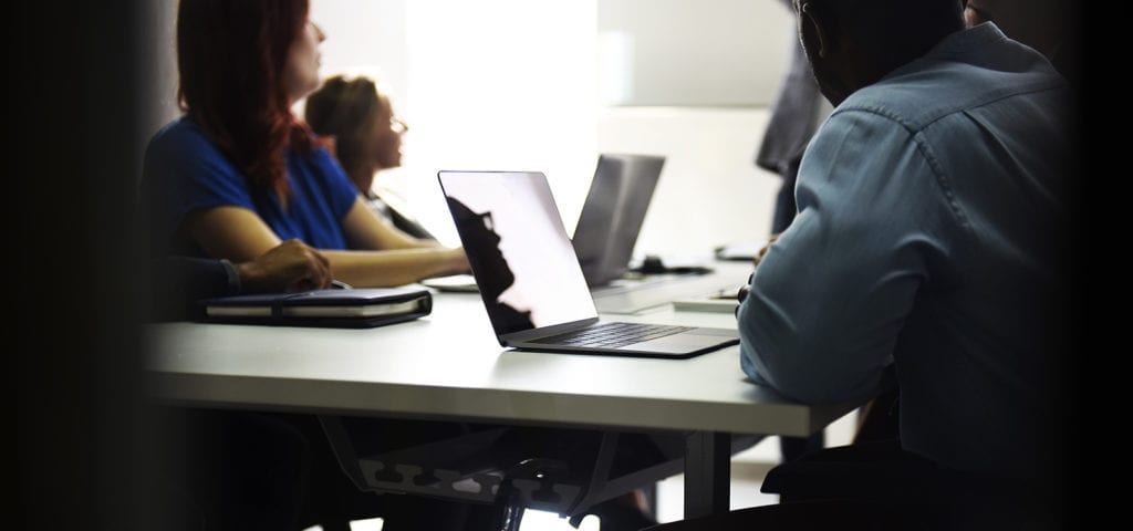 Business partners working together at a table on laptops.