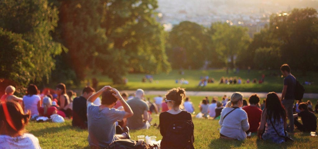 A group of people outside enjoying the sunshine in a crowded park.