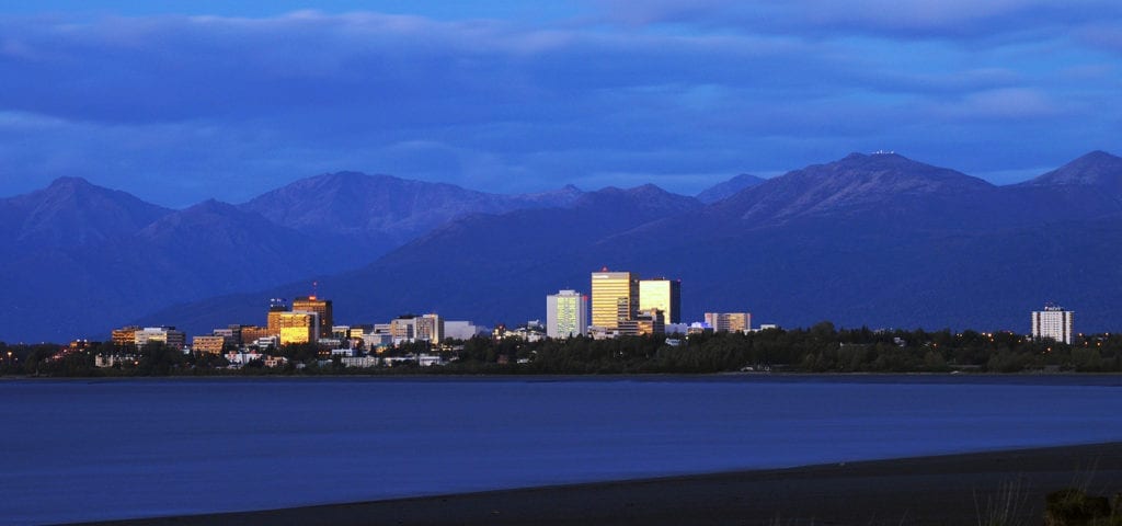 The Anchorage, Alaska city skyline, photographed from across a stretch of flat water.