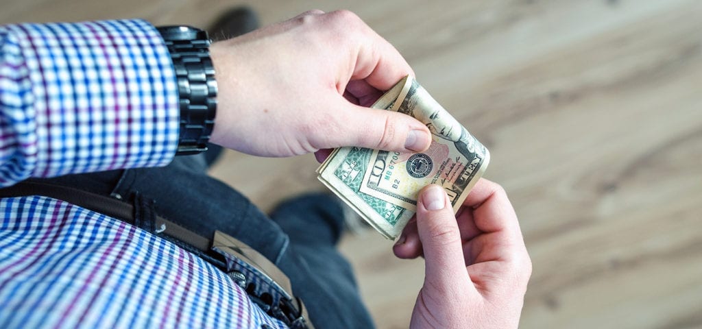 A man folds a $100 bill in front of him.