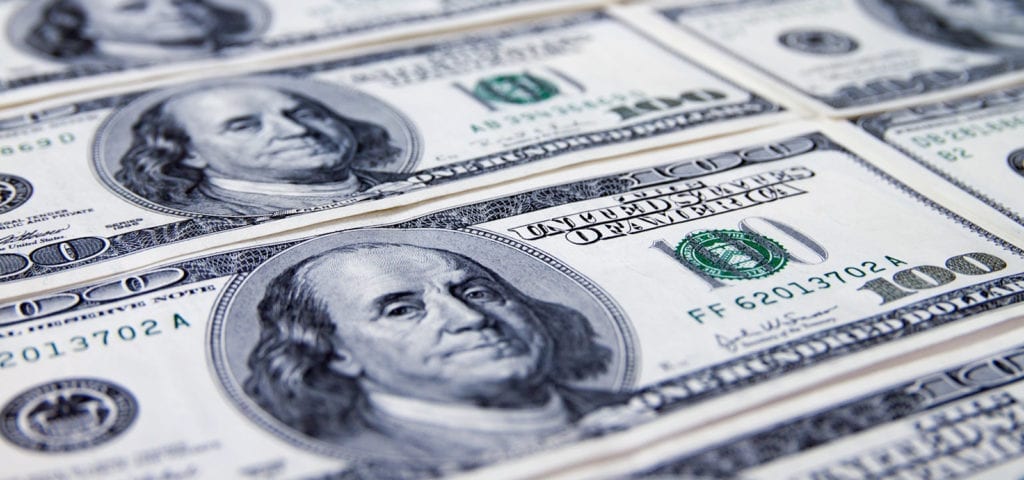 Sheets of $100 dollar bills lying flat on a surface.